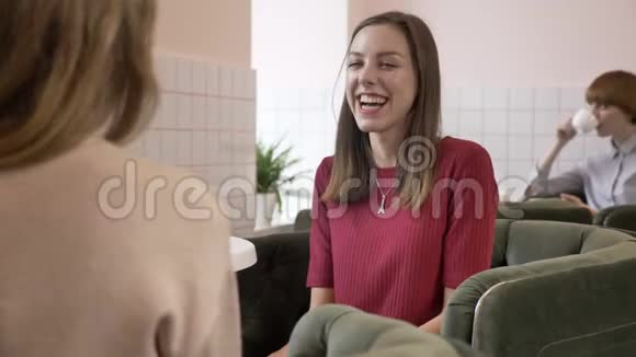 三个白种人年轻女孩坐在咖啡馆里微笑交谈对话惊讶的情绪八卦的概念视频的预览图