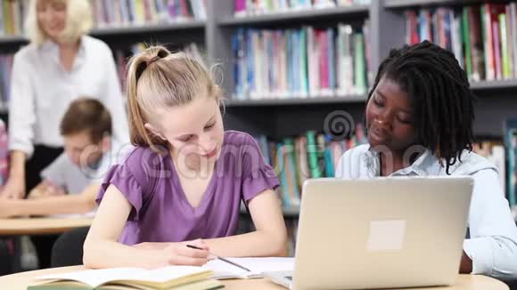 教师帮助两名在笔记本电脑上工作的女高中生视频的预览图