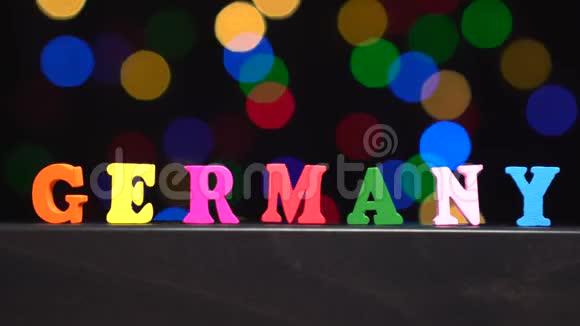 色彩斑斓的德国由多种色彩的木制字母在抽象模糊的灯光前背景视频的预览图