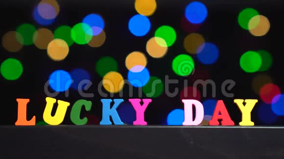 彩色的文字幸运的一天从多种颜色的木制字母前面抽象模糊的灯光背景视频的预览图