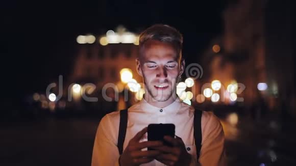 年轻迷人的男人用智能手机走在夜城的街道上交流旅游旅游约会商务视频的预览图