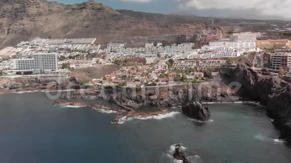 空中射击山度假小镇内有许多酒店棕榈树等植被蓝色的海洋和海浪拍打着视频的预览图