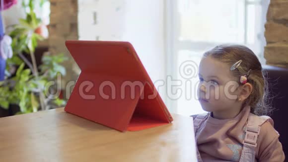 可爱的女孩在咖啡馆看动画片等妈妈视频的预览图