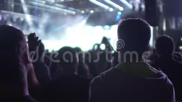 一群痴迷的歌迷在舞台上等着看最喜欢的乐队夜生活视频的预览图