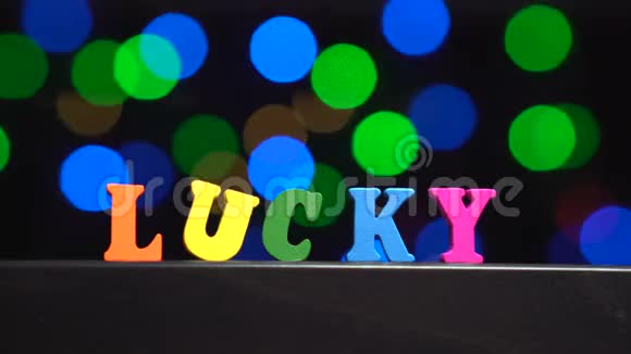 抽象模糊灯光背景下的彩色木信中的幸运一词视频的预览图