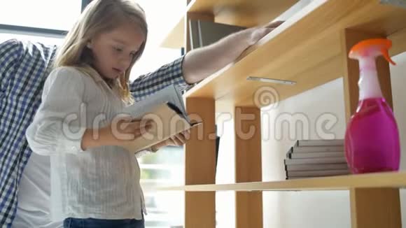 可爱的小女孩在打扫卫生时整理书籍视频的预览图