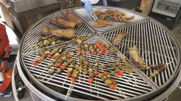一个大的圆形烤架被分成几个部分围绕着它的轴线在烤架上有各种各样的肉和蔬菜视频的预览图