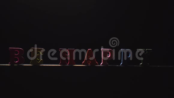 色彩斑斓的字要快乐从多种颜色的木制字母出现在灯光下视频的预览图