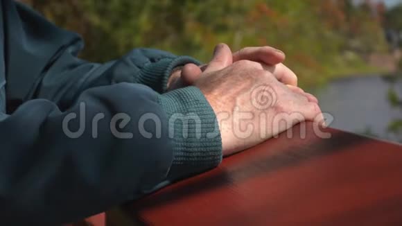 老年人的手在美丽的自然森林河流背景下的特写视频的预览图
