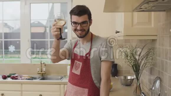 穿围裙的年轻人在厨房喝酒视频的预览图