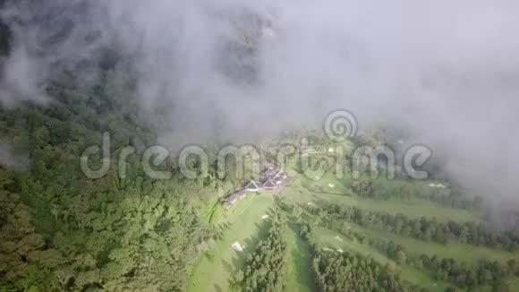 从鸟瞰森林中的高尔夫球场高尔夫球场的视野从云层中打开视频的预览图