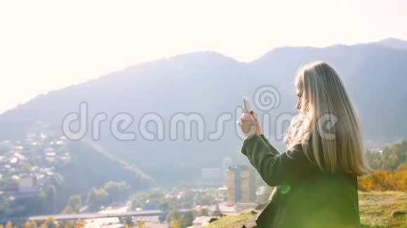 少女拍照从山顶移动电话景观城市景观女游客站在悬崖上享受视频的预览图
