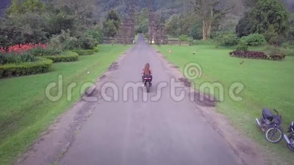 丛林中笔直的野路的空中景色摩托车骑在前面两个人骑摩托车一对夫妇视频的预览图