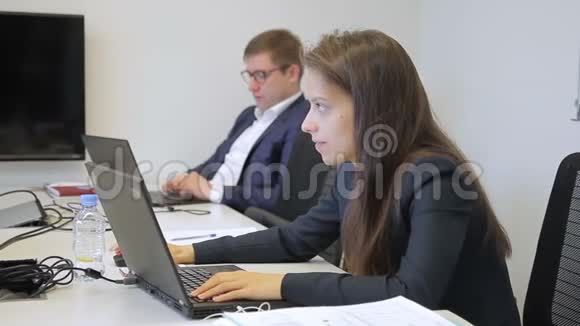 年轻的同事正在工作坐在桌子旁随身携带笔记本电脑视频的预览图