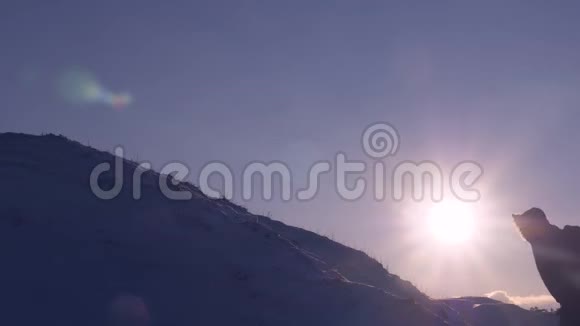 登山者在明亮的阳光下爬上雪山游客在美丽的天空的背景下爬到山顶男人视频的预览图