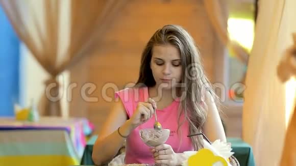 在咖啡馆里吃冰淇淋的年轻女人视频的预览图