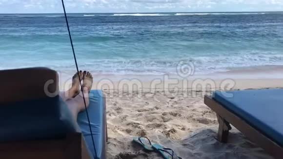 年轻的woamn在印度尼西亚巴厘岛热带海滩的沙滩椅上放松视频的预览图