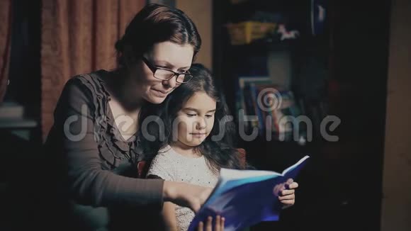 小女孩和一个成年女人正在读一本书他们在晚上被教一个睡前故事母亲和视频的预览图
