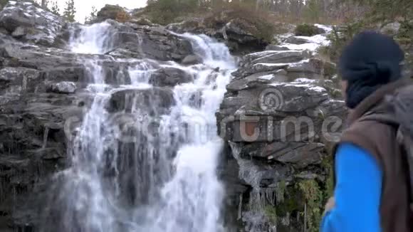 一个人带着背包沿着山区路线旅行他到达了美丽的瀑布看了看继续前进积极主动视频的预览图