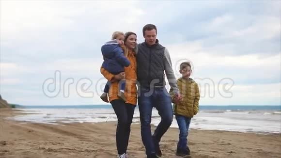 快乐的父母和两个孩子在海岸散步视频的预览图