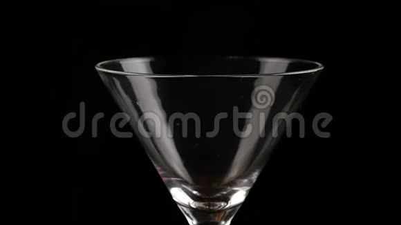 酒精在黑暗的背景上倒入玻璃杯中准备鸡尾酒和派对概念慢动作视频的预览图