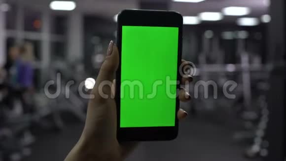 女性检查智能手机应用程序中燃烧卡路里的数量绿色屏幕视频的预览图