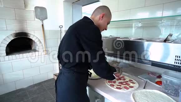 一个年轻的披萨师在餐厅的厨房准备披萨厨师把鸡片放进里面视频的预览图