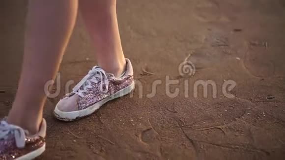 一个穿着运动鞋女孩的腿在海滩上行走视频的预览图