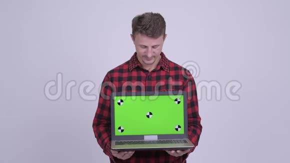 快乐的留胡子的时髦男人展示和看手提电脑视频的预览图