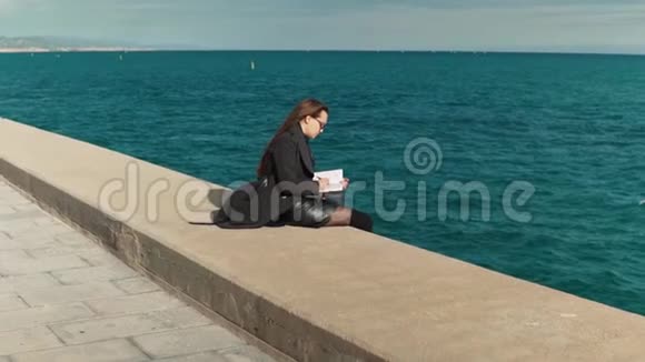 女人在海边的户外素描书上画素描慢镜头视频的预览图