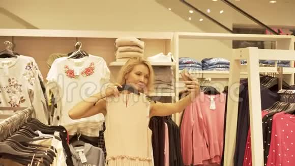 一个年轻女孩在电话里自拍在服装店里试穿衣服视频的预览图