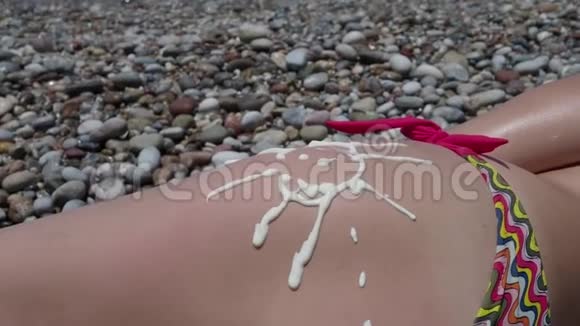一个年轻女孩在海滩上的臀部涂了防晒霜4K视频的预览图