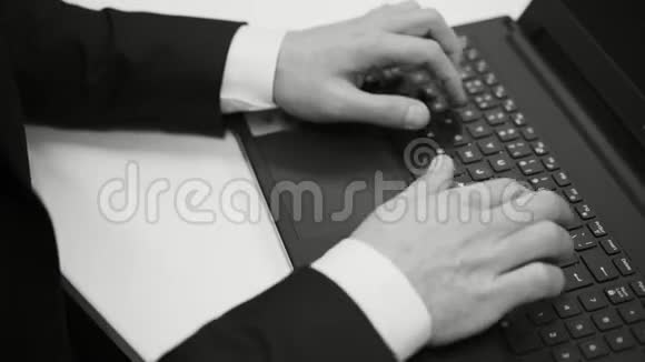 黑白电影中的白人商人坐在办公桌前打手提电脑视频的预览图