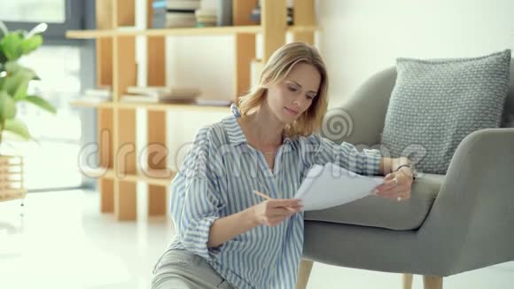 漂亮的年轻女士在家里检查商务文件视频的预览图