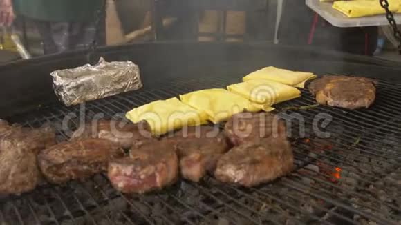 大块的肉放在一个大圆烤架上厨师用铅笔把皮塔面包放在烤架上视频的预览图