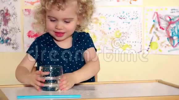 有趣的女孩把水倒在桌子上用手掌溅起兴奋的湿孩子视频的预览图