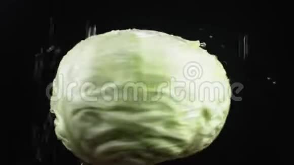 白菜头特写水滴落在黑色背景上旋转的苹果上超级慢动作视频的预览图