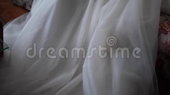 漂亮的新娘穿着白色长裙坐在房间里的沙发上视频的预览图