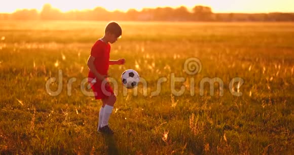 日落时分年轻的足球运动员在球场上和球混在一起视频的预览图