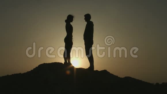 一对年轻的情侣在山上拥抱在夕阳中亲吻视频的预览图
