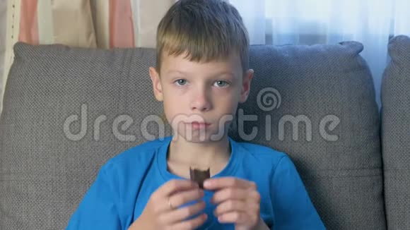 小男孩坐在沙发上吃巧克力糖不健康饮食观念视频的预览图