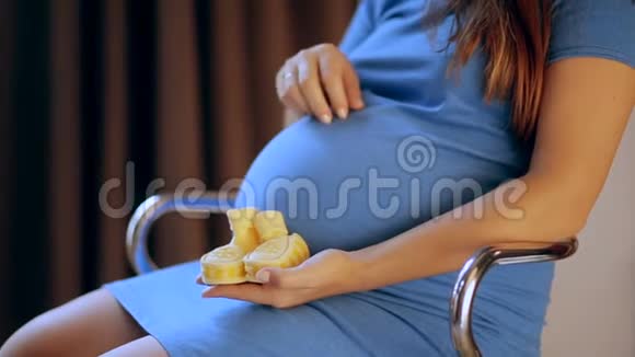 怀孕快乐的女人手里拿着婴儿鞋妈妈在等她的孩子孕妇的肚子怀孕生育观念视频的预览图