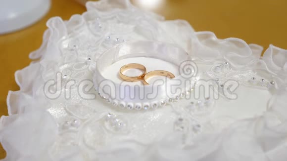 金色的结婚戒指放在白色的盒子里放在美丽的枕头上上面有花边和莱茵石视频的预览图
