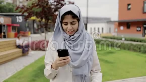 戴头巾走路看智能手机的年轻女性视频的预览图