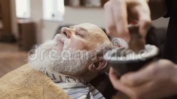 理发师把剃须膏涂在成熟男人的脸上视频的预览图