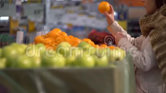 一个女孩在商店的蔬菜货架上选择橘子视频的预览图
