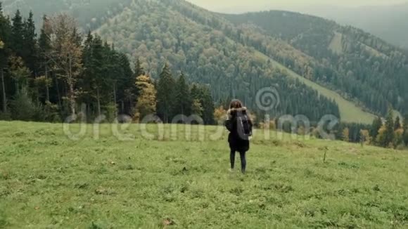 镜头跟随年轻女孩徒步旅行者在山上行走举起手臂飞向空中视频的预览图