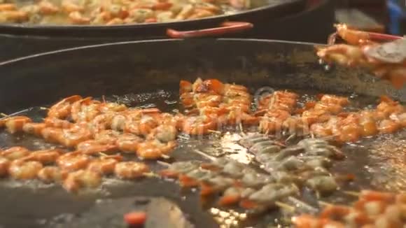 烤虾在一个大煎锅里煎烧烤时炸海鲜在街头美食节上炸虾烧烤视频的预览图