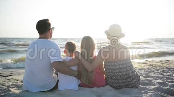 母亲父亲儿子和女儿在海边拥抱的后景视频的预览图