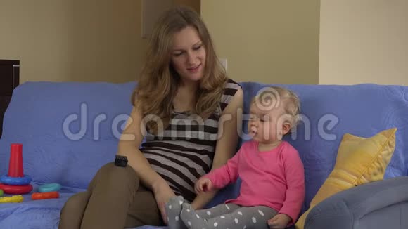 快乐妈妈看电视宝贝女儿坐在室内沙发上4K视频的预览图